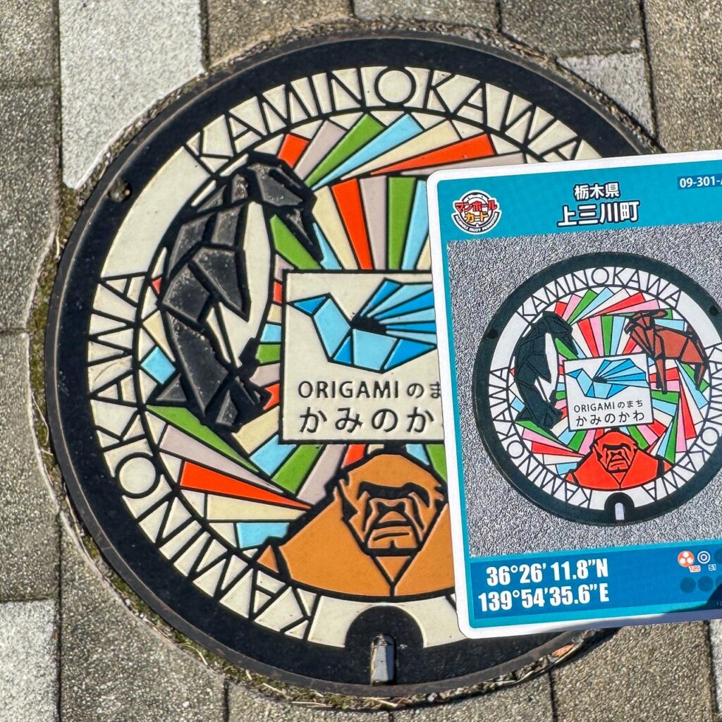 上三川町A「ORIGAMI」のデザインマンホール蓋と対応するマンホールカードを現地で並べた様子