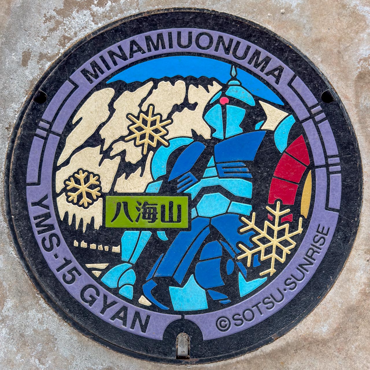 YMS-15 ギャンのガンダムマンホール。八海山の雪山をモチーフとしたデザイン