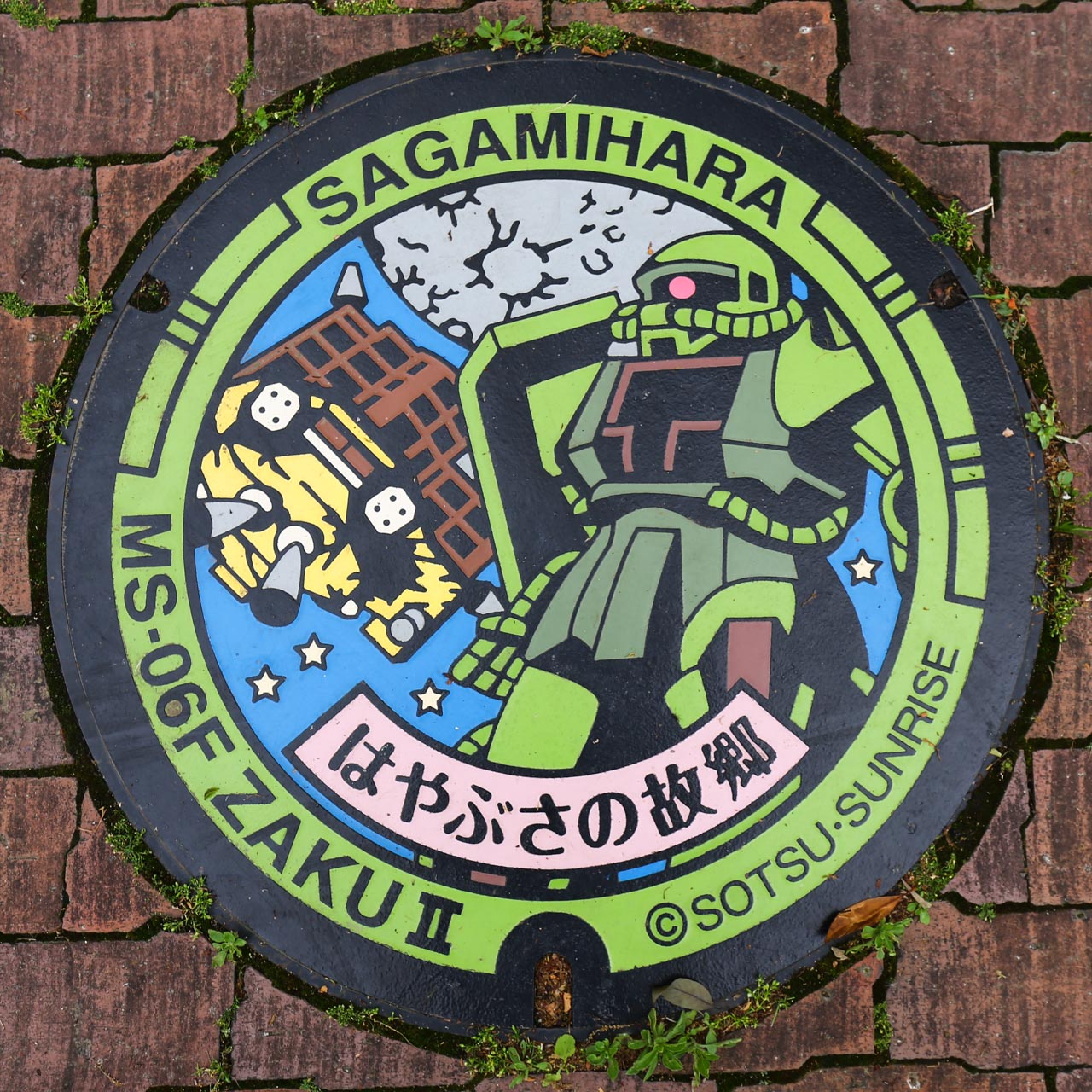 はやぶさの故郷 ザクⅡのガンダムマンホール。探査船はやぶさとザクⅡをモチーフとしたデザイン