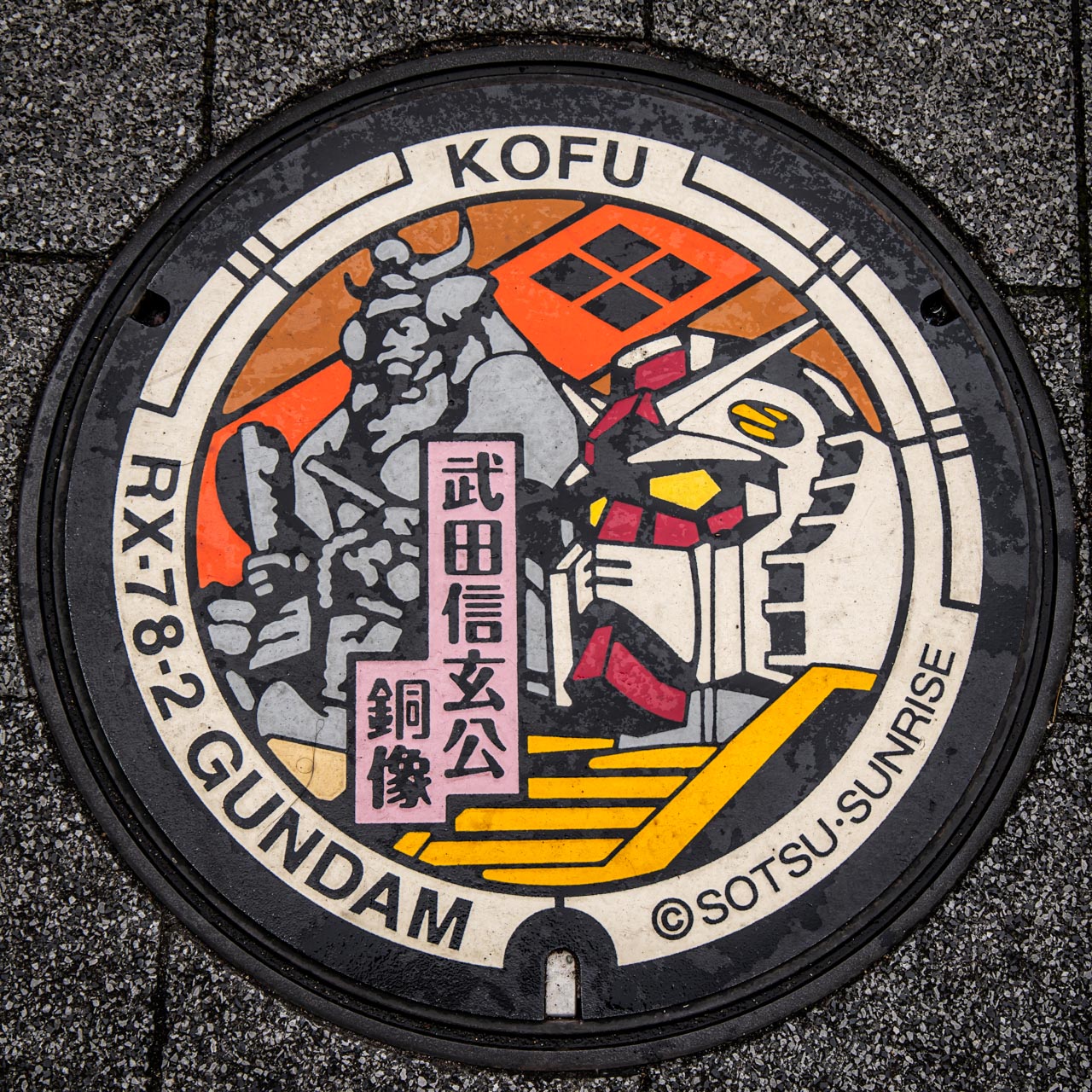 山梨県甲府市に設置されたRX-78-2ガンダムのガンダムマンホール。武田信玄公の銅像をモチーフとしたデザイン