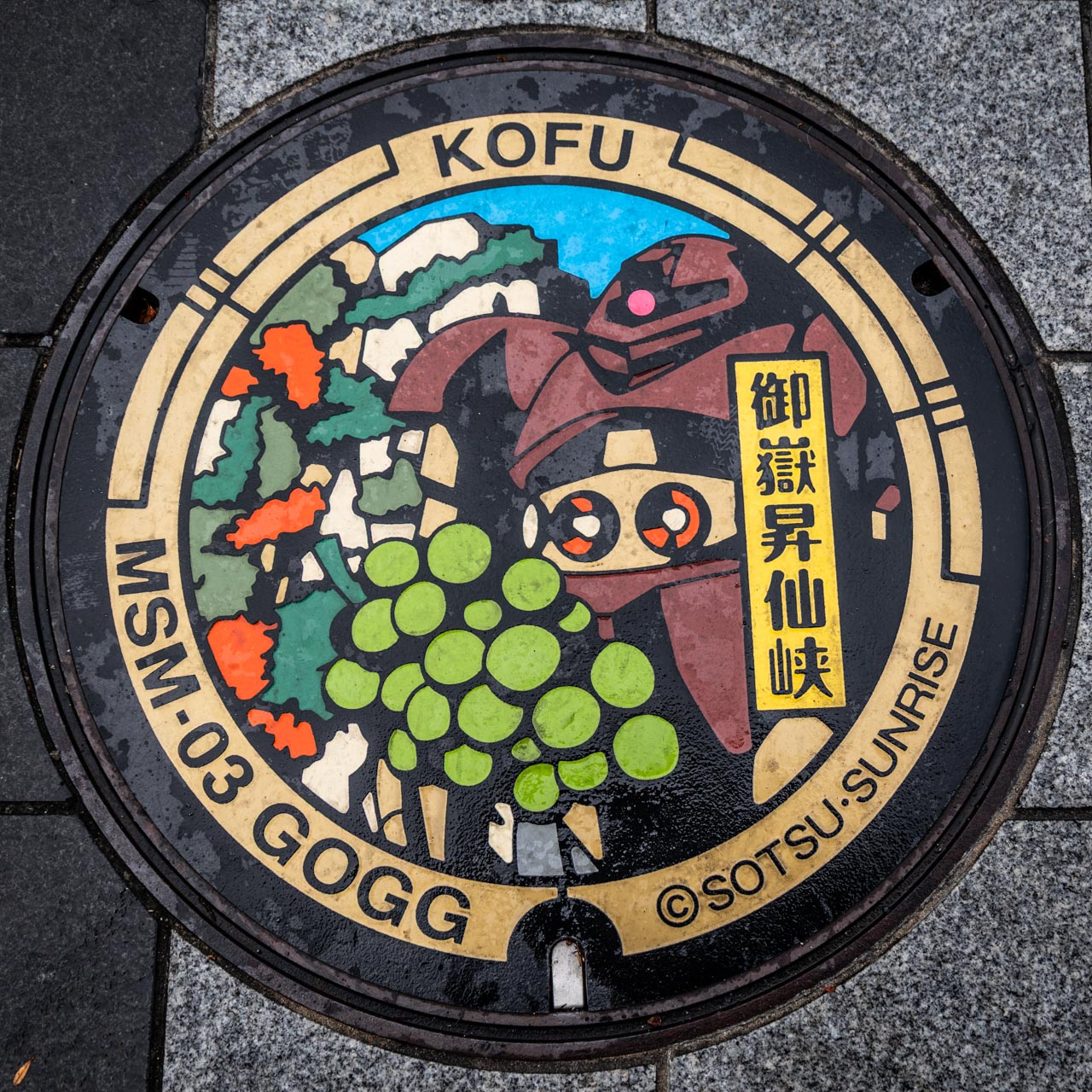 山梨県甲府市に設置されたゴッグのガンダムマンホール。日本遺産・御嶽昇仙峡と、甲府名産のシャインマスカットをあしらったデザイン